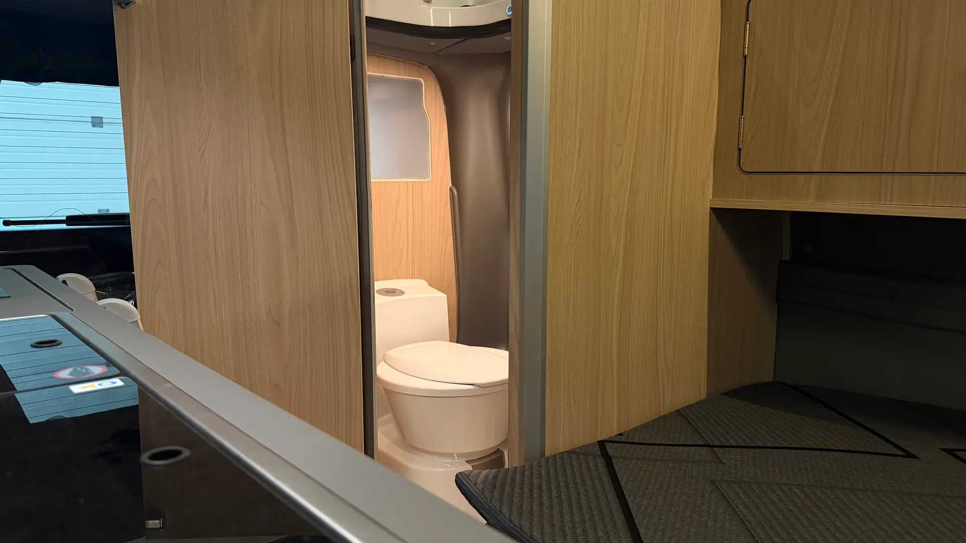 Die geöffnete Badkabine des Ephesus hinter der Holztür mit Kassettentoilette und Duschbereich